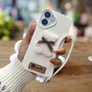 A Single-Pack Plush Teddy Bear Phone Case with a Bow, Available in White And Brown. It Comes with a Wrist Strap And Features a Simple And Elegant Faux Leather Texture That Is Anti-Slip And Fingerprint-Resistant. Made with TPU