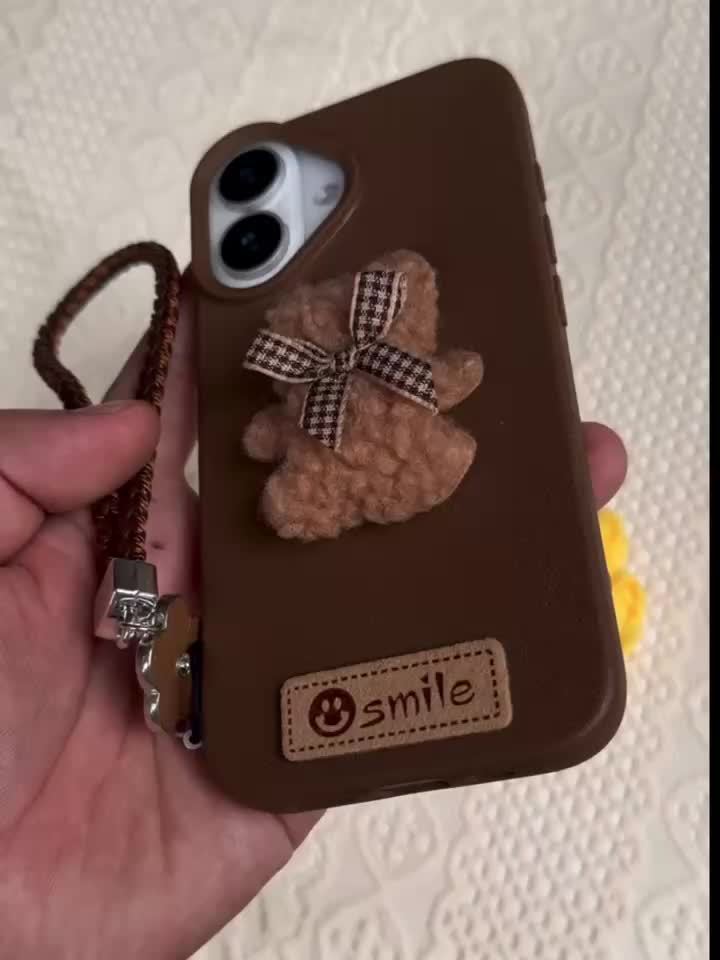 A Single-Pack Plush Teddy Bear Phone Case with a Bow, Available in White And Brown. It Comes with a Wrist Strap And Features a Simple And Elegant Faux Leather Texture That Is Anti-Slip And Fingerprint-Resistant. Made with TPU