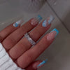 A Set of 24 Full-Cover Press-On Fake Nails Featuring Blue Wave Designs, Sparkling Diamonds, And Cloud Patterns in a Blue French Style, Along with Three-Dimensional Gel Stripes. These Medium Square-Shaped Fashionable Press-On