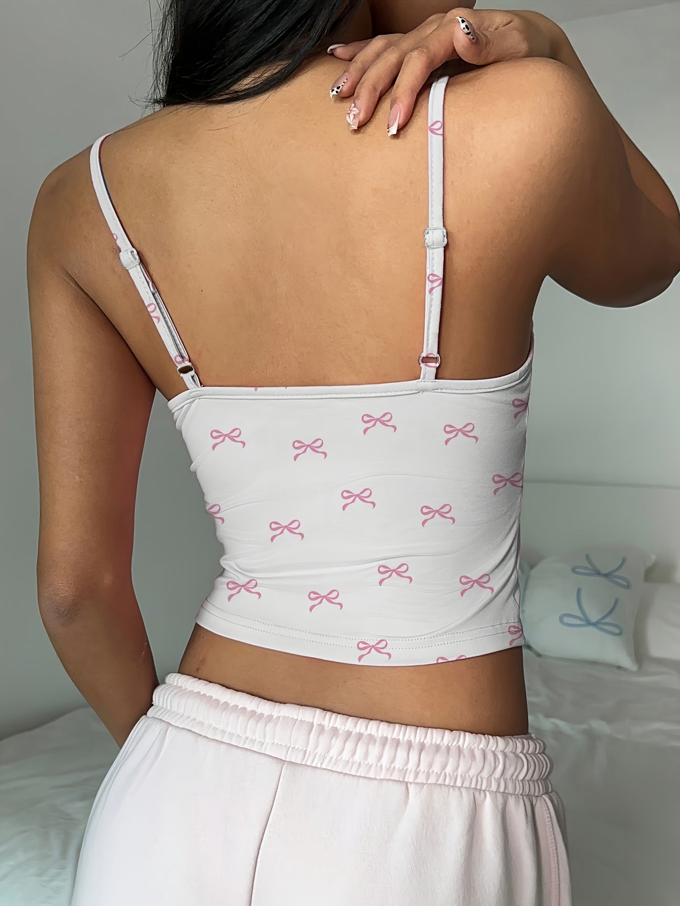 A Sleeveless Fitted Tank Top for Women Featuring a Cute Pink Bow Design.